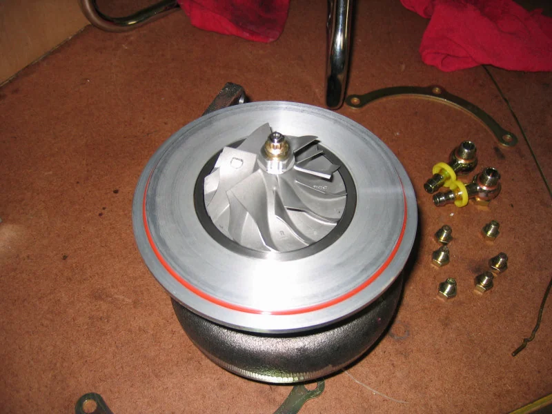 Garrett GT30 turbocharger compressor wheel installed on its center housing (CHRA), oil-line fittings at right. Real photograph used as a representative reference, not the specific N54 TD03/TD04 part.