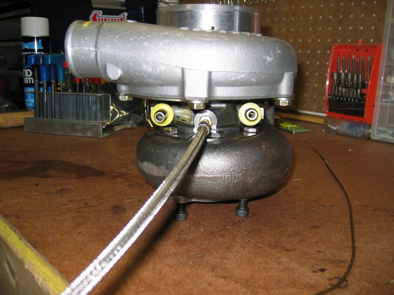 Close view of a turbocharger CHRA's oil-feed banjo fitting and feed line — real reference photograph