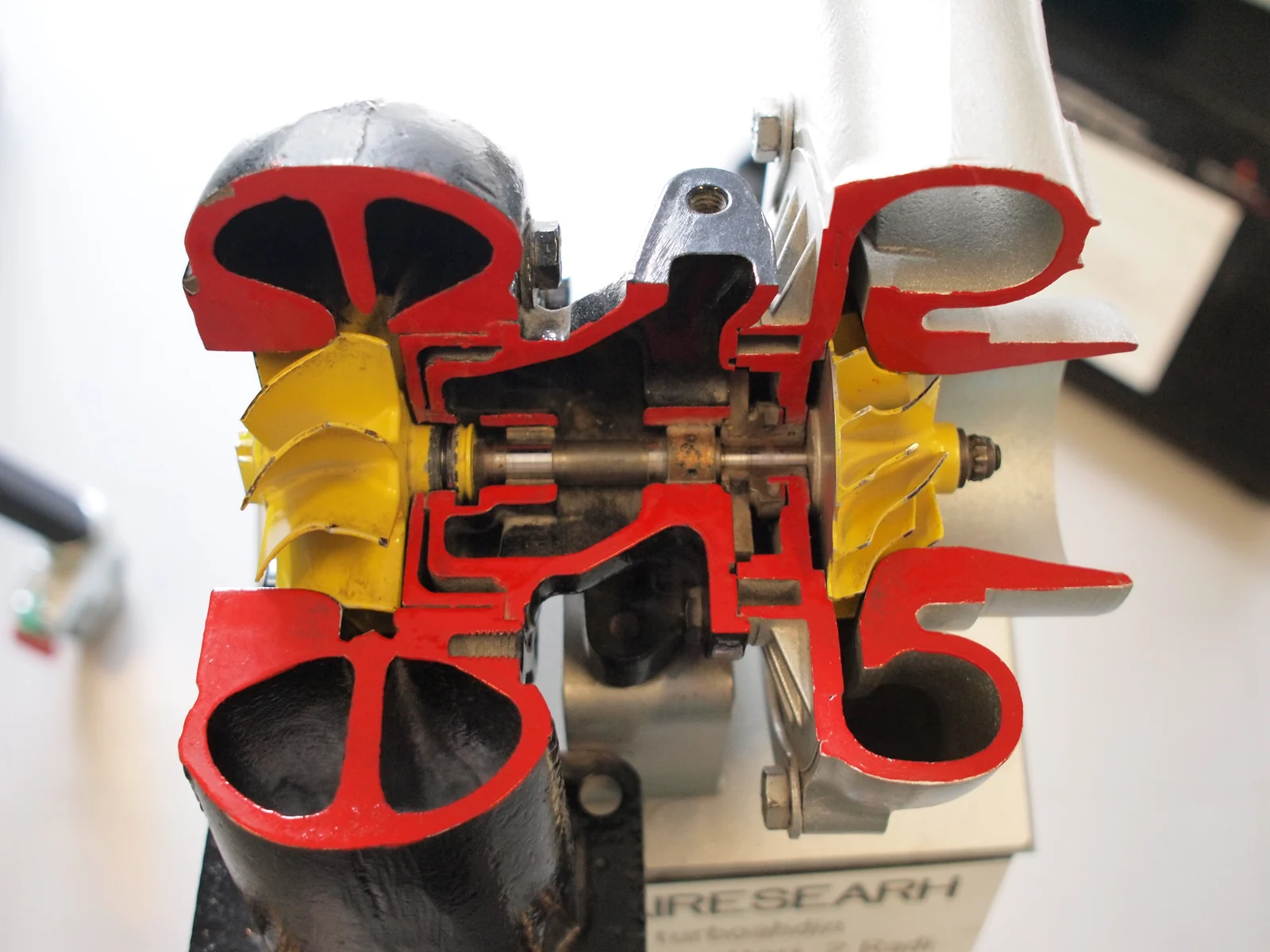Physically sectioned Garrett AiResearch turbocharger showing the real shaft running between the compressor and turbine wheels — real reference photograph